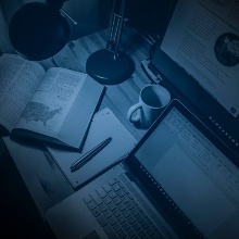 Schreibtischlampe beleuchtet Schreibtisch mit Laptop, Buch, Notizblock und Tasse